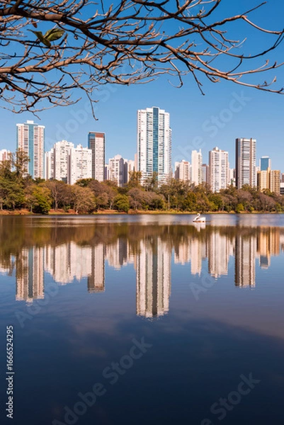 Obraz Urban view of the city of Londrina, Brazil, with a lake in the foreground, a strip of vegetation in the middle, and residential skyscrapers in the background.