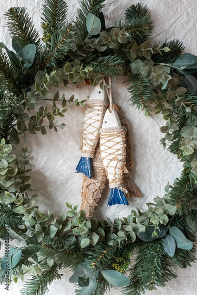 Fototapeta green Christmas wreath with wooden fish decoration on paper texture background.