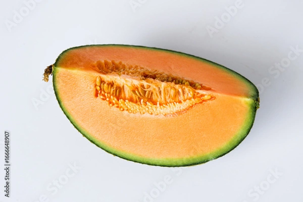 Fototapeta Top view of a single wedge of ripe cantaloupe, showing the vibrant orange flesh and the small cluster of seeds, isolated on a white background.