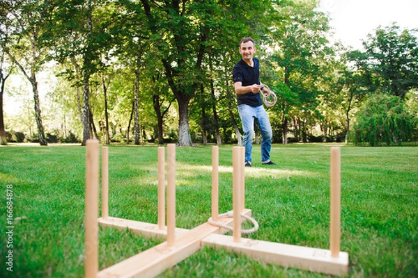 Fototapeta Outdoor games - guy playing ring toss in a park.