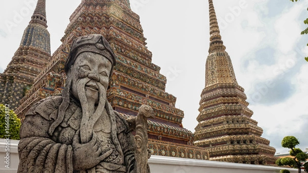 Fototapeta Stone Guardian Statue with Colorful Buddhist Stupas in Traditional Temple Courtyard