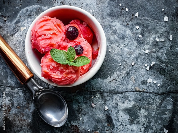 Fototapeta strawberry ice cream with red berries and mint in a white jar seen from above and dark background