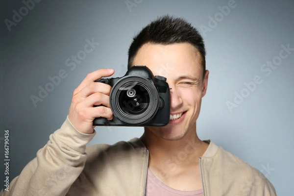 Fototapeta Handsome photographer with camera on gray background