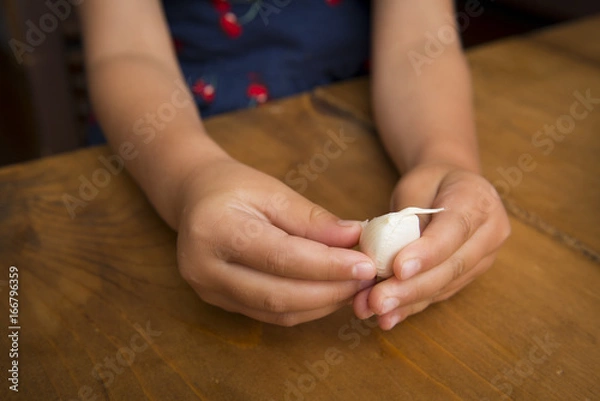 Fototapeta Children's hand peeling the garlic