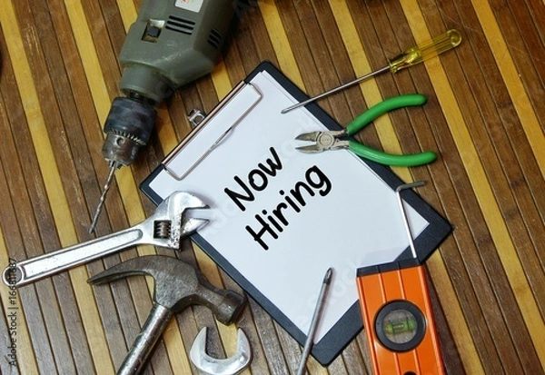 Fototapeta Construction work concept. Notepad and various tools with word  now hiring