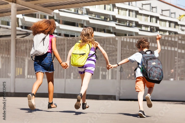 Fototapeta Three kids run to school view from behind
