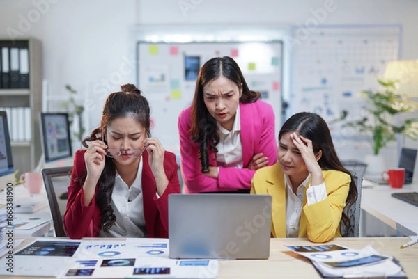 Fototapeta Business team having problems and feeling stressed about project deadline, looking at laptop in office meeting room