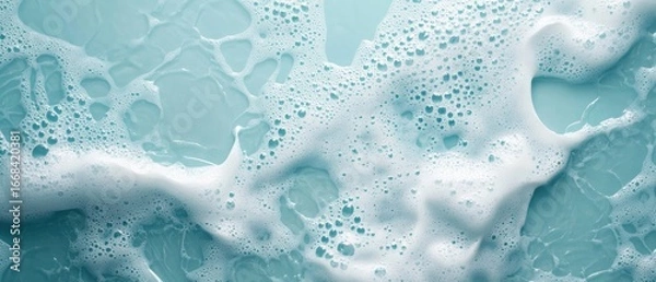 Fototapeta White foam bubbles floating on a light blue liquid surface, creating an abstract textured background