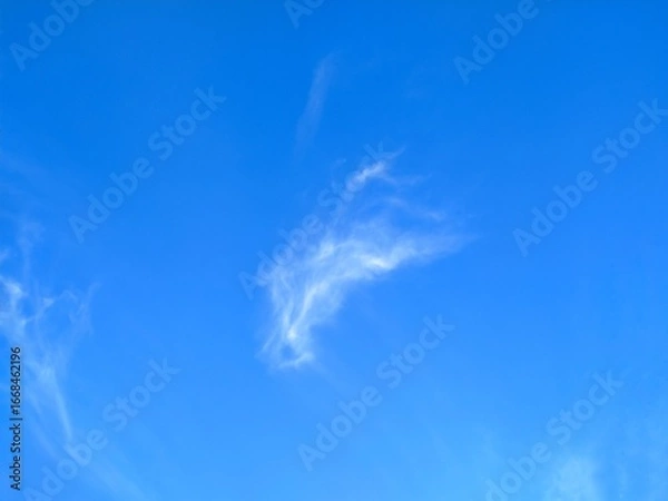 Fototapeta Wispy white cloud formation against a vivid blue sky on a clear day. Delicate, airy cirrus clouds creating a soft, dreamy, and peaceful atmosphere perfect for nature and weather concepts.