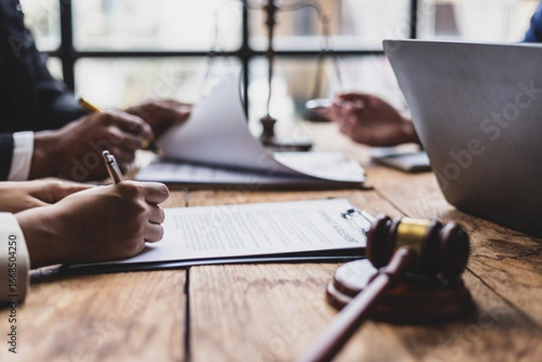 Fototapeta Lawyers and clients reviewing contract agreement terms before signing. Business partners carefully review contract terms before signing at a wooden table.