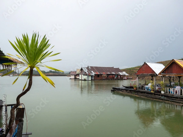 Fototapeta Floating raft restaurant on a reservoir with mist and drizzle in rural Thailand.