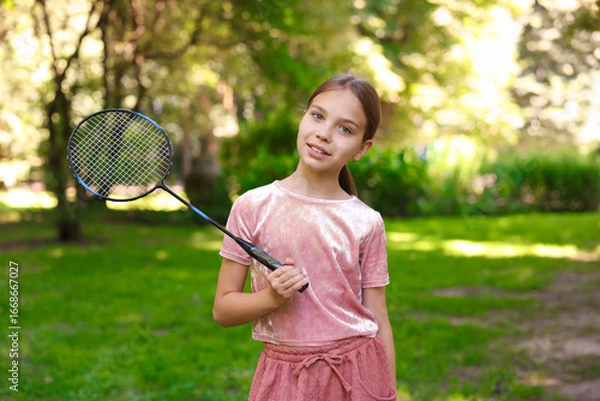 Fototapeta Portrait of smiling little girl with badminton racket in park