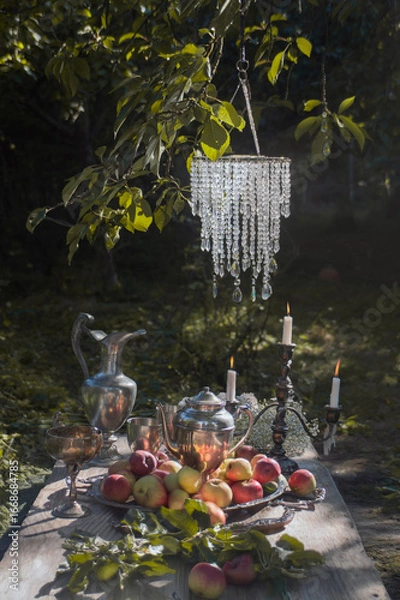 Fototapeta Rustic garden still life with freshly picked apples on a wooden table surrounded by greenery. Natural light, organic and seasonal harvest theme.