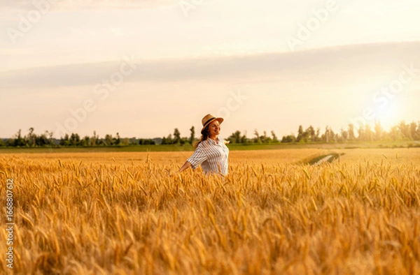 Fototapeta Happy woman enjoying rural nature in wheat field in countryside at golden hour
