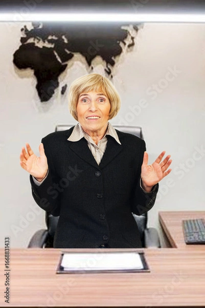 Fototapeta Businesswoman in formal attire gestures with hands in office featuring a map on the wall.