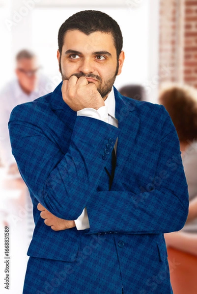 Fototapeta Man in professional attire appears to be contemplating something important, set in an office environment. His pensive expression conveys deep thoughtfulness and decision-making in a corporate context.