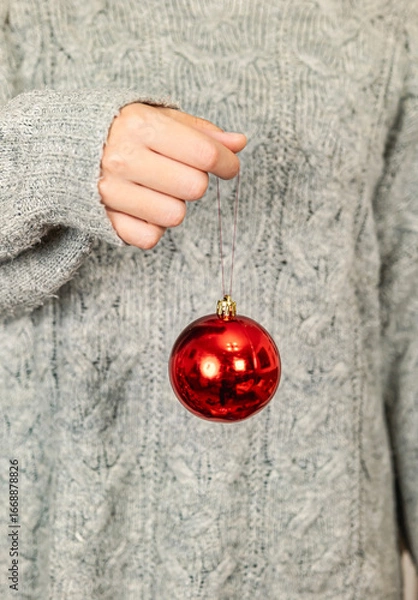 Fototapeta Hand holding shiny red Christmas bauble
