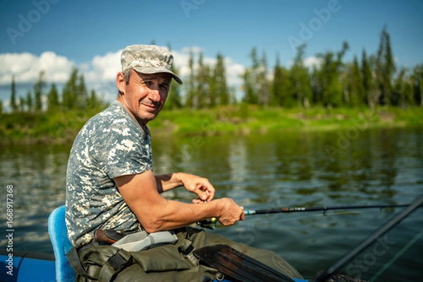 Fototapeta Close-up of an elderly fisherman catching fish with a spinning rod