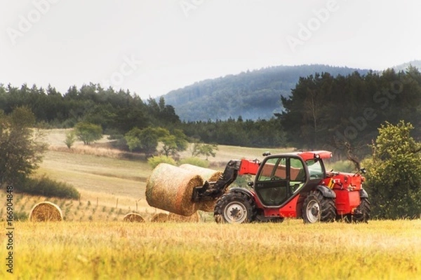 Fototapeta Telescopic collector straw collector on field in the Czech Republic. Work on an agricultural farm. Collecting straw bales.