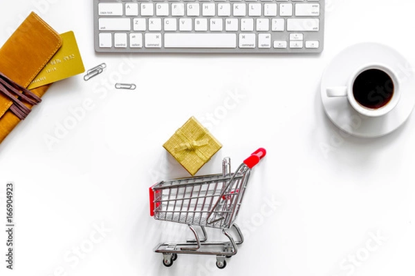 Obraz Buy gift in webstore. Gift box near shopping trolley, wallet and keyboard on white background top view copyspace