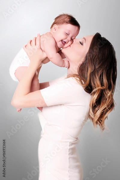 Fototapeta happy family at home. Mother holding baby in bedroom in cozy weekend morning