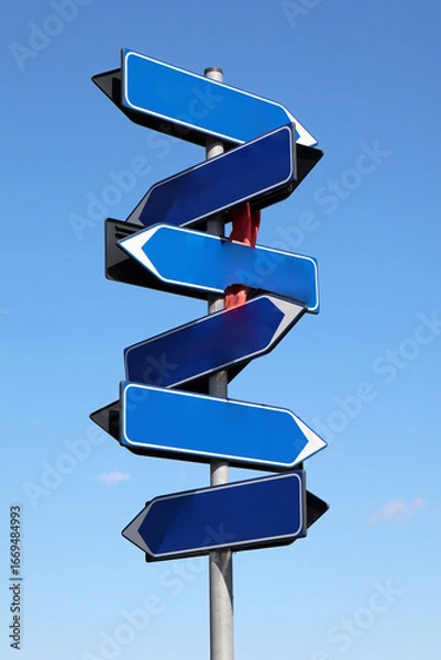 Fototapeta Multiple blank blue arrow signs pointing in various directions against a clear blue sky, symbolizing choices and future paths.