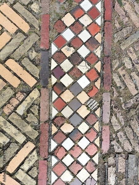 Fototapeta Close-up detail of bright colored brick and tile pavers laid out in contrasing geometric patterns