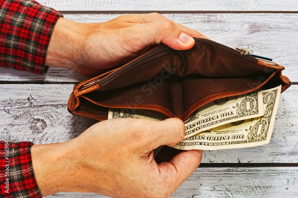 Fototapeta Man in work shirt holding wallet with just two dollars