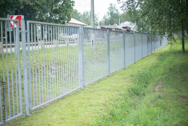 Fototapeta A fence along the territory. A gray fence enclosing the stadium. Fencing on the street.