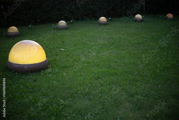 Fototapeta Lamps in the park. Spherical lamps are installed on the lawn. Illumination of the green zone.
