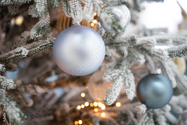 Fototapeta Delicate frosted ornaments hang from lush evergreen branches, illuminated by warm lights, creating a festive atmosphere perfect for welcoming the new year.