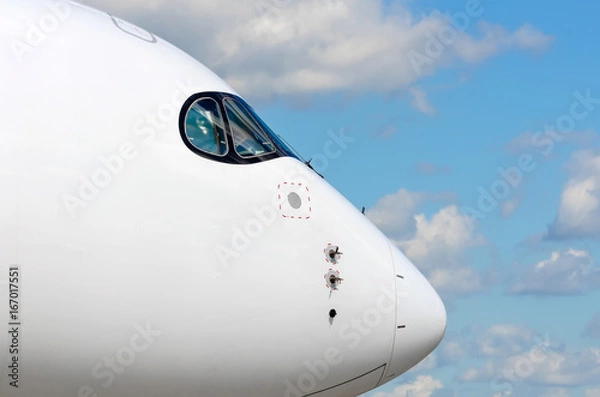 Fototapeta Passenger airplane nose cockpit in blue clouds sky