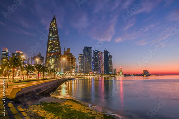 Obraz Doha city business downtown center panorama illuminated at sunrise, with modern skyscrapers and sea in the foreground, Qatar