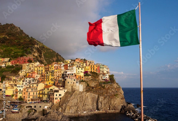 Fototapeta Manarola village in Cinque Terre with italian flag in foreground