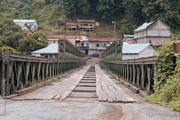 Fototapeta An old narrow Bailey bridge with steel trusses and a wooden deck, serving as a single-lane crossing in a small hilly village of Dapchhuah in Mizoram