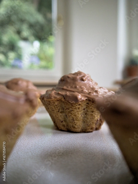 Fototapeta Close-up of homemade hazelnut muffins with chocolate frosting.