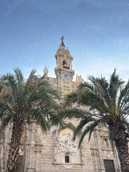 Obraz Church of San Juan through palm trees and blue sky on a sunny day in Plaza Mercat in Valencia, Spain. Valencia landmark.