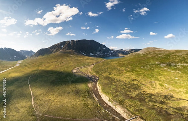 Fototapeta Aerial view showcases Blåhøa rising above Blåhøtjønna lake in Trollheimen mountain range. This Nordic landscape offers stunning hiking trails and rough terrain, perfect for summer adventures