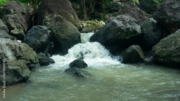 Fototapeta Cascading Water Over Rocks in a Serene Stream
