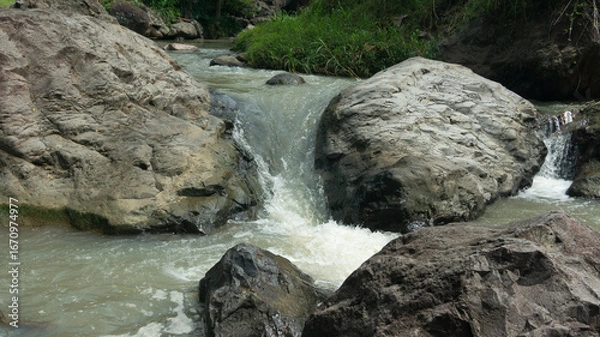 Fototapeta Cascading Water Over Rocks in a Serene Stream