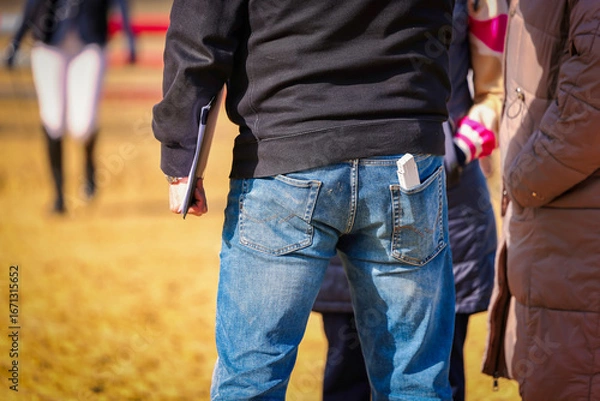 Fototapeta Man, course builder, close-up from behind with folding rule and clipboard in hand and trouser pocket.