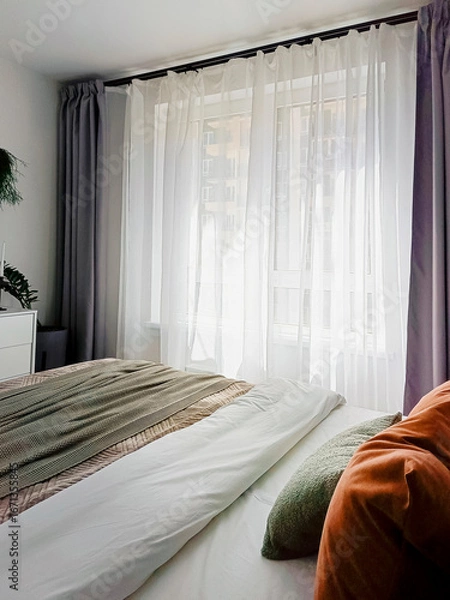 Fototapeta Fragment of a room with a large window close-up. Bed, pillows - home interior.