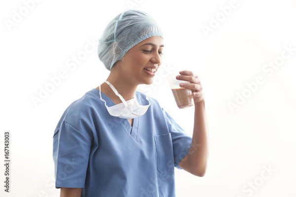 Obraz Happy young female surgeon drinking tea isolated over white background 