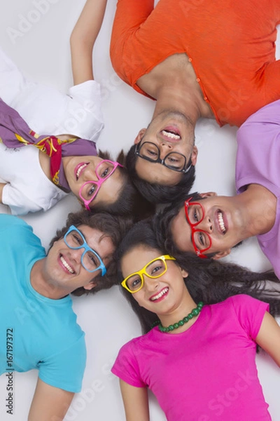 Fototapeta Directly above shot of young friends lying with their heads together on white background