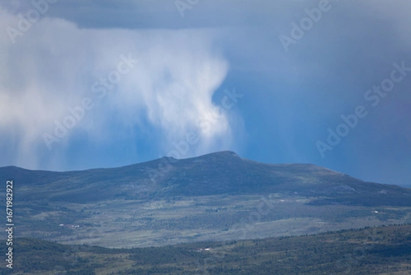 Obraz Mountain landscape under dramatic sky with rain clouds sweeping across the horizon