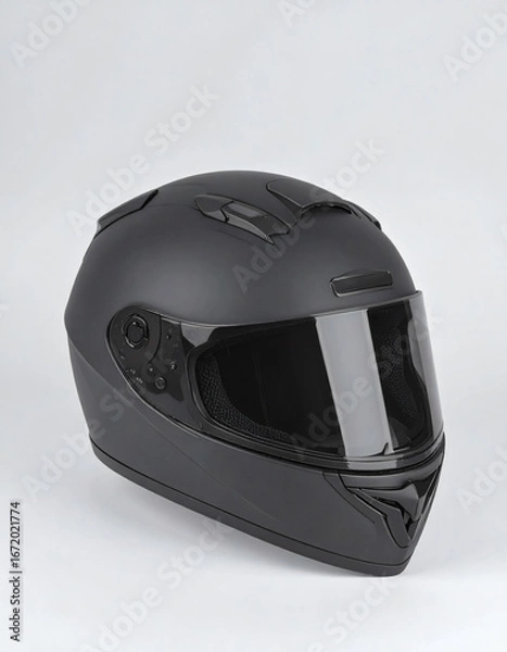 Fototapeta A matte black full-face motorcycle helmet with a tinted visor is displayed against a plain white background.