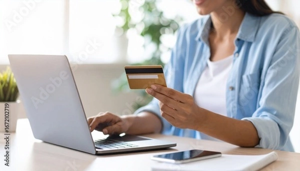 Fototapeta Young Woman Engaged in Online Shopping Using Credit Card While Sitting at Her Laptop in Cozy Room