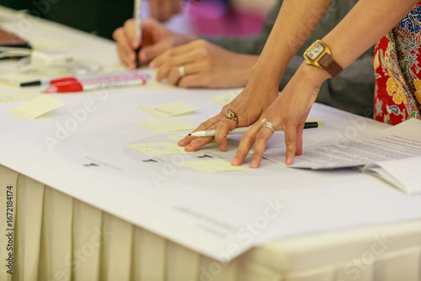 Fototapeta Collaborative Brainstorming Session: Colleagues Pointing and Discussing Ideas on Sticky Notes