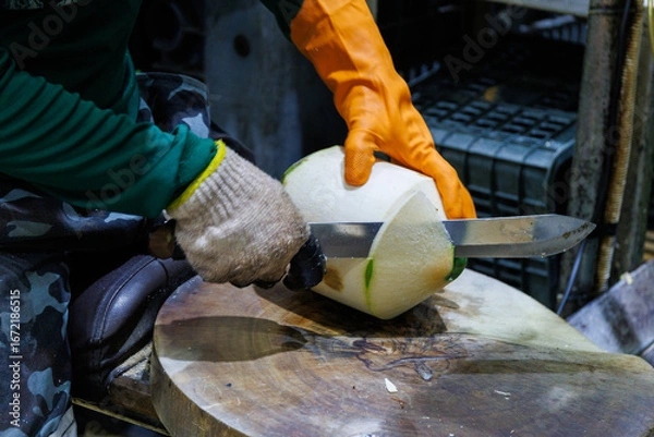 Fototapeta Skilled Hands Preparing Fresh Green Coconut with a Sharp Knife in a Processing Plant