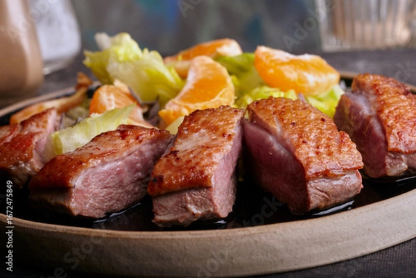 Obraz Sliced seared duck breast with salad and orange sauce.
